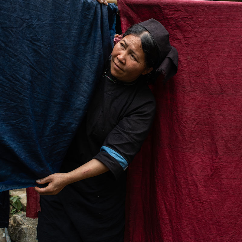 Chị Nhất hangs banana-silk fabrics dyed with indigo and lac resin to dry.